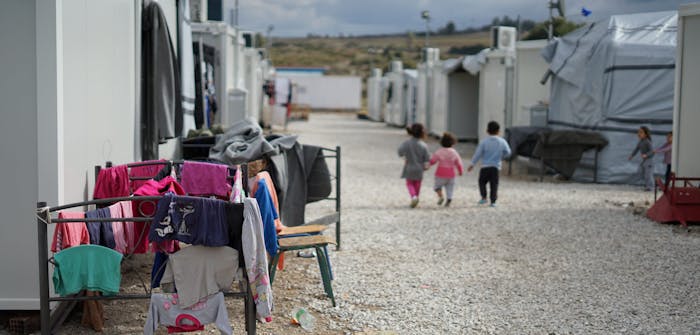Drie kinderen lopen in een vluchtelingenkamp.