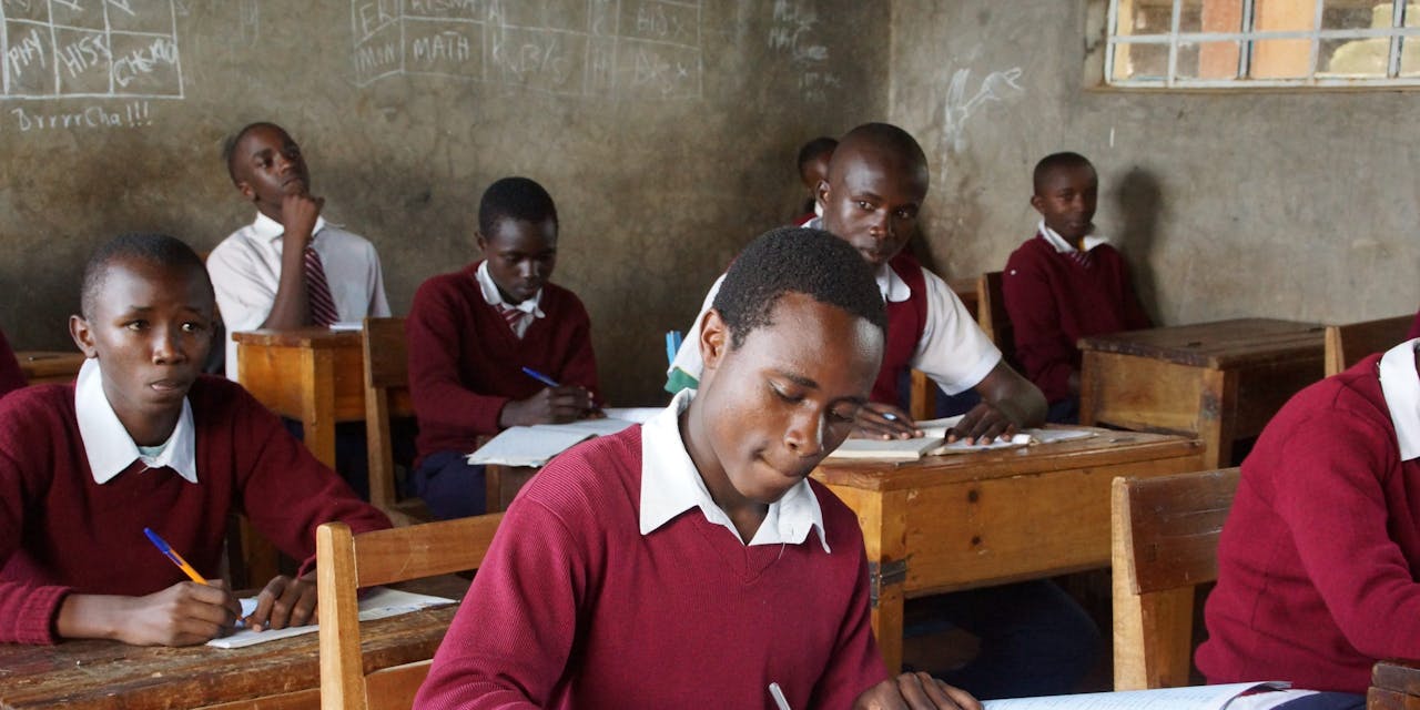 Een leerling in Kenia schrijft in zijn schrift in de klas.