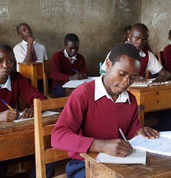 Een leerling in Kenia schrijft in zijn schrift in de klas.