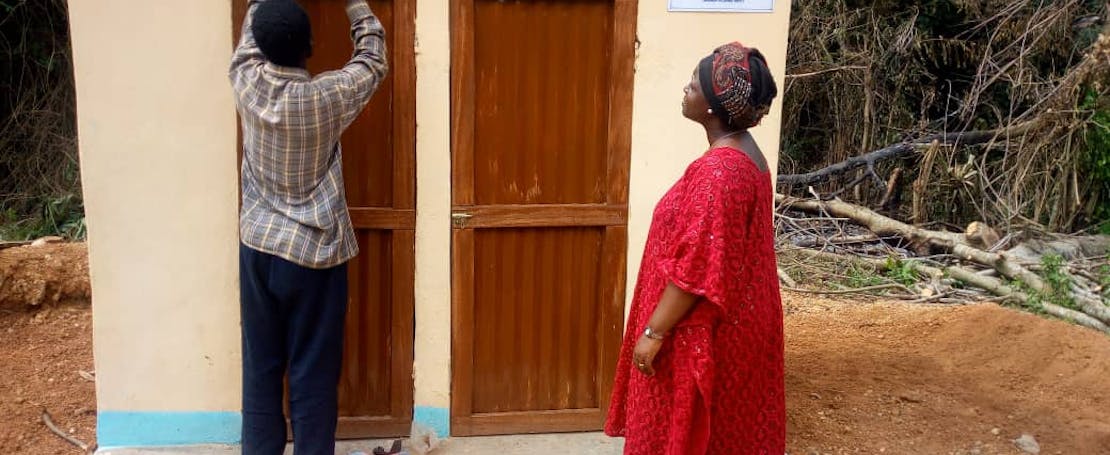 Een man en een vrouw leggen de laatste hand aan een nieuw toiletgebouw in Togo.