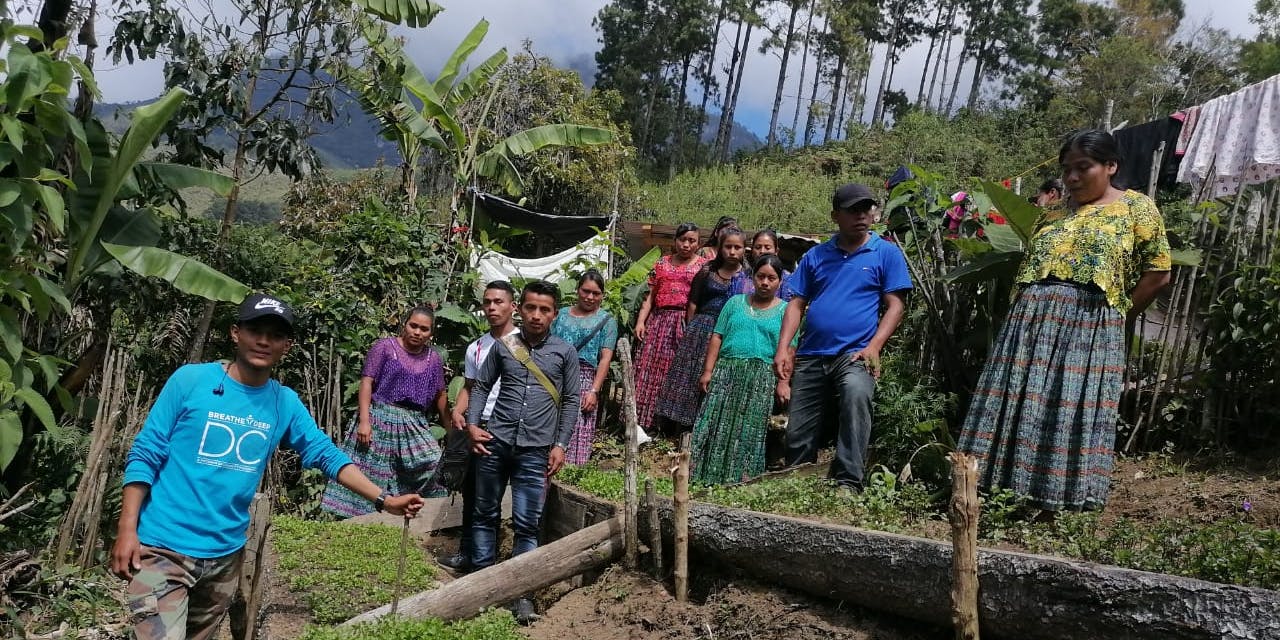 Een groep mensen poseert bij een groentetuin in Guatemala.