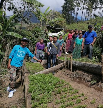 Een groep mensen poseert bij een groentetuin in Guatemala.