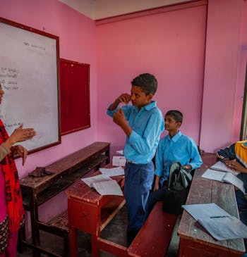 Een roze klaslokaal met leerlingen en een docent in Nepal.
