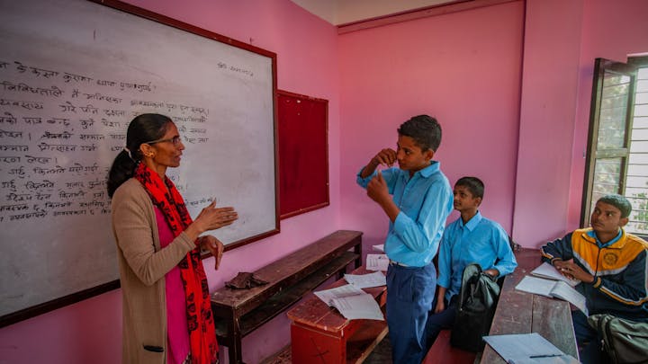 Een roze klaslokaal met leerlingen en een docent in Nepal.