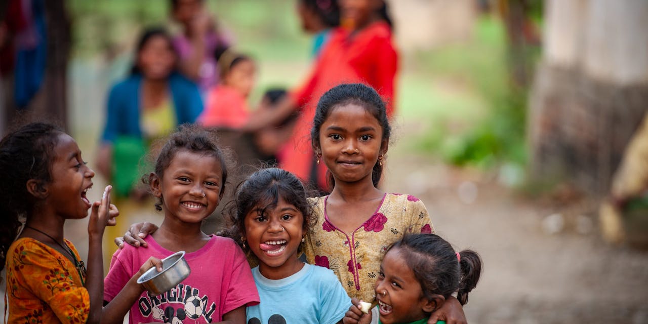 5 jonge kinderen kijken lachend in de camera in Nepal.