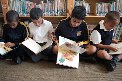 Vier jongens lezen een boek in een bibliotheek in Zuid Afrika.