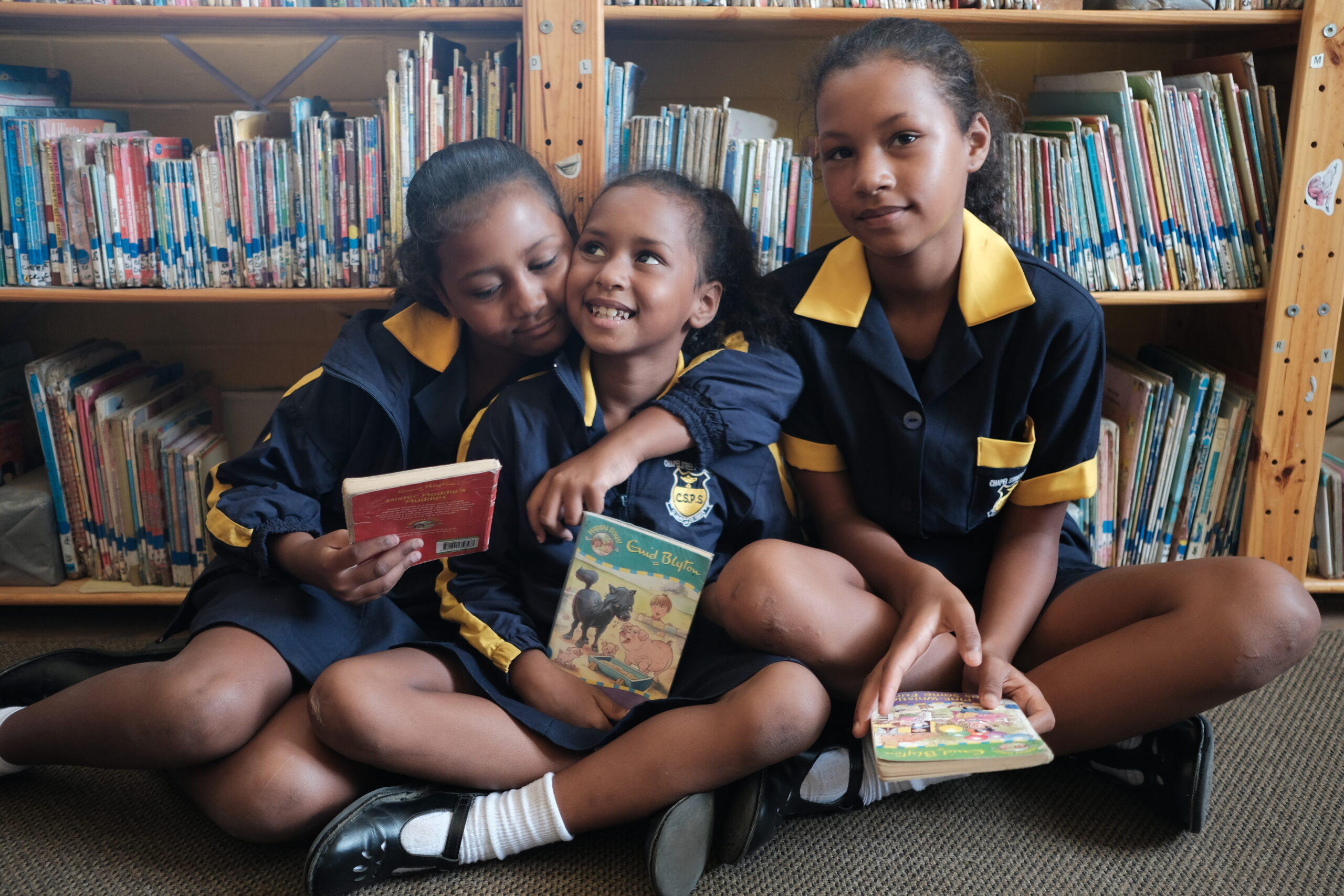 Drie meisjes met boeken in een bibliotheek in Zuid Afrika.