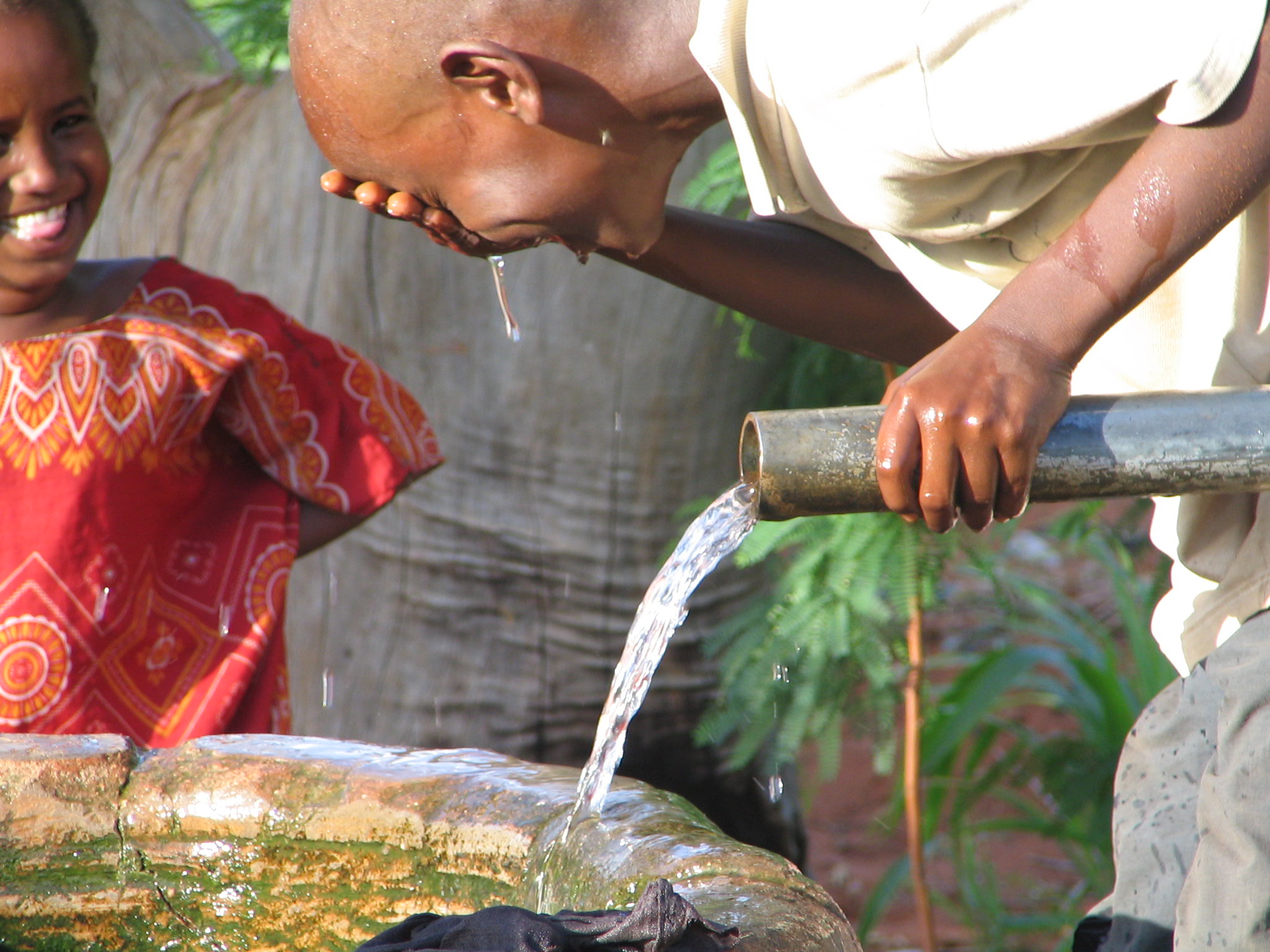 Een jongetje wast zijn gezicht met water in Kenia.