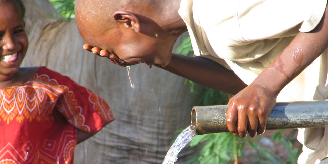 Een jongetje wast zijn gezicht met water in Kenia.