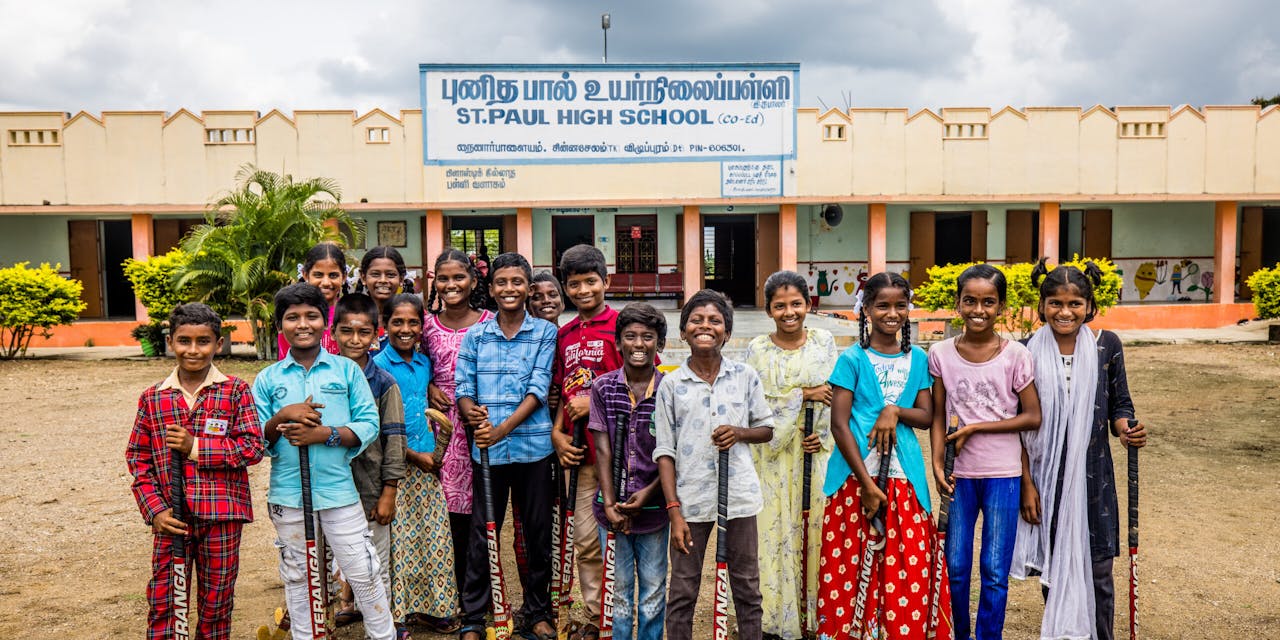 Een klas met kinderen poseert voor hun schoolgebouw in India.