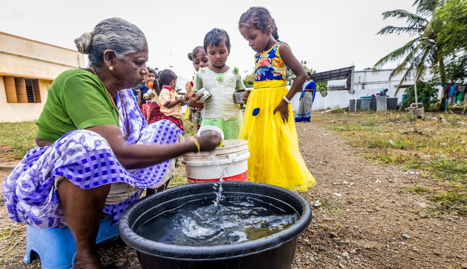 Een vrouw haalt water om te wassen uit een teil in India.