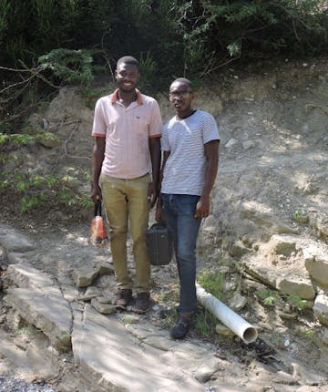 Twee mannen bij een waterleiding in Haïti.