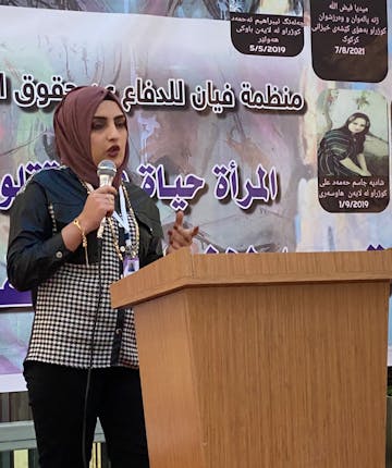 Een vrouw achter een spreekgestoelte in Irak.