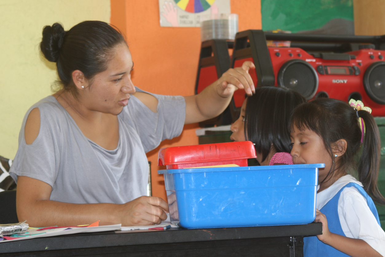Een juf op school met twee kinderen in Mexico.