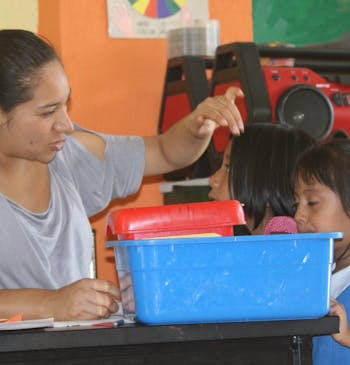 Een juf op school met twee kinderen in Mexico.