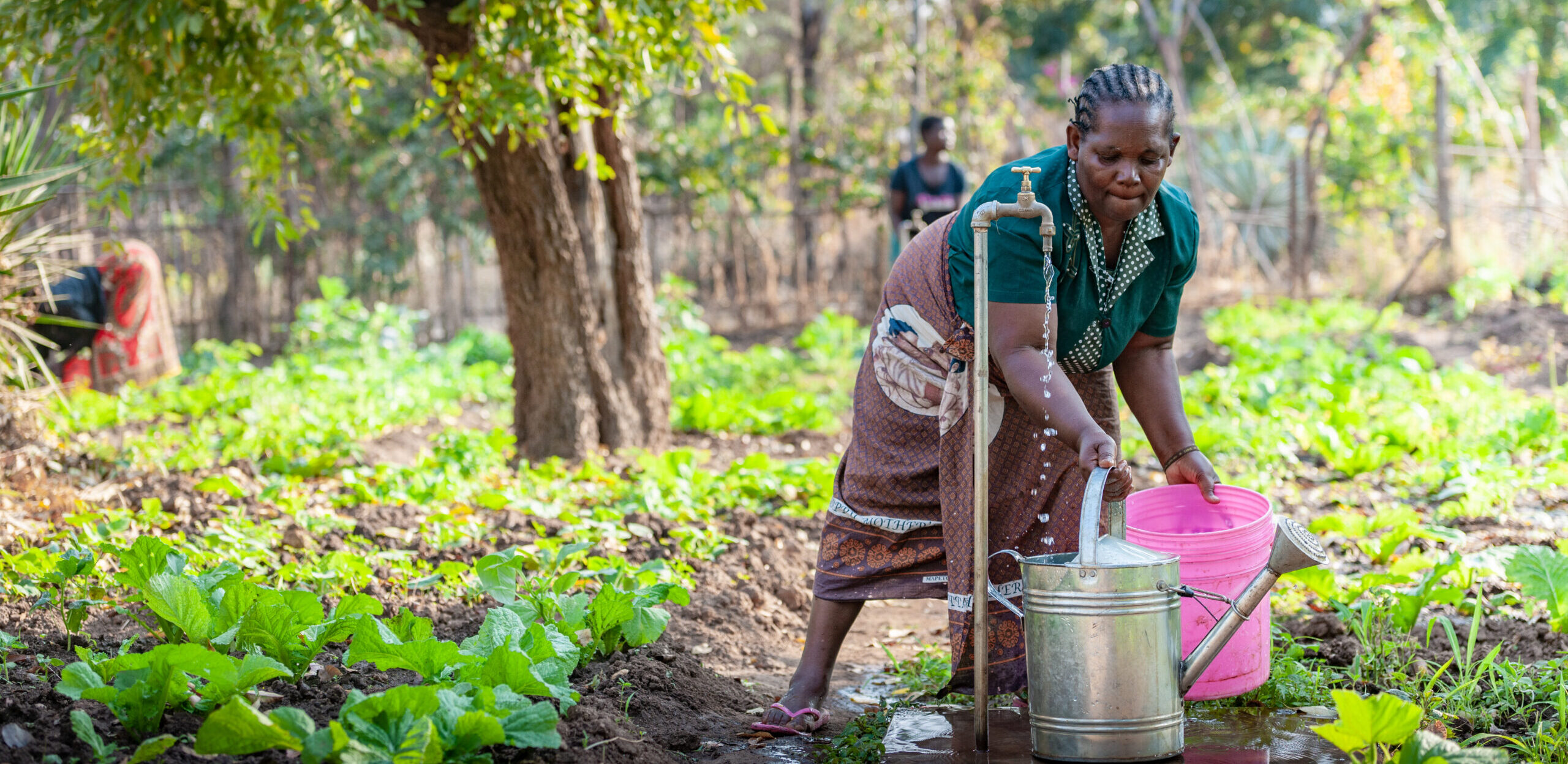 Een vrouw tapt water uit de kraan bij haar moestuin.