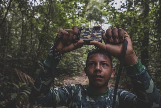 Een jongen houdt een camera omhoog in het Amazonegebied.