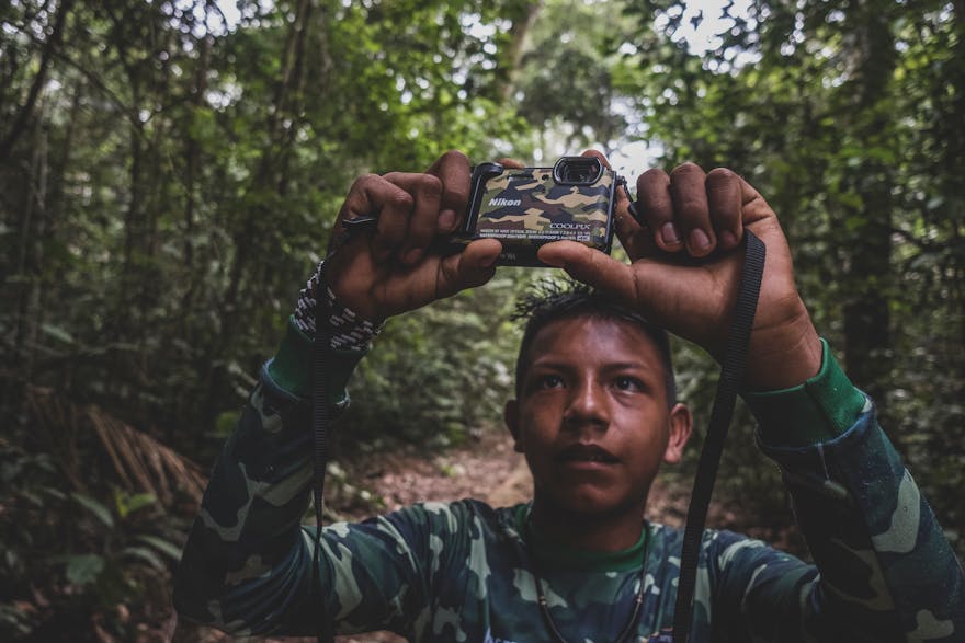 Een jongen houdt een camera omhoog in het Amazonegebied.