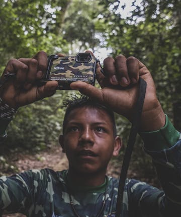 Een jongen houdt een camera omhoog in het Amazonegebied.