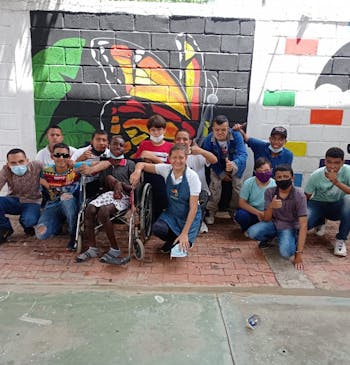 Een groep kinderen poseert voor een muurschildering in Colombia.