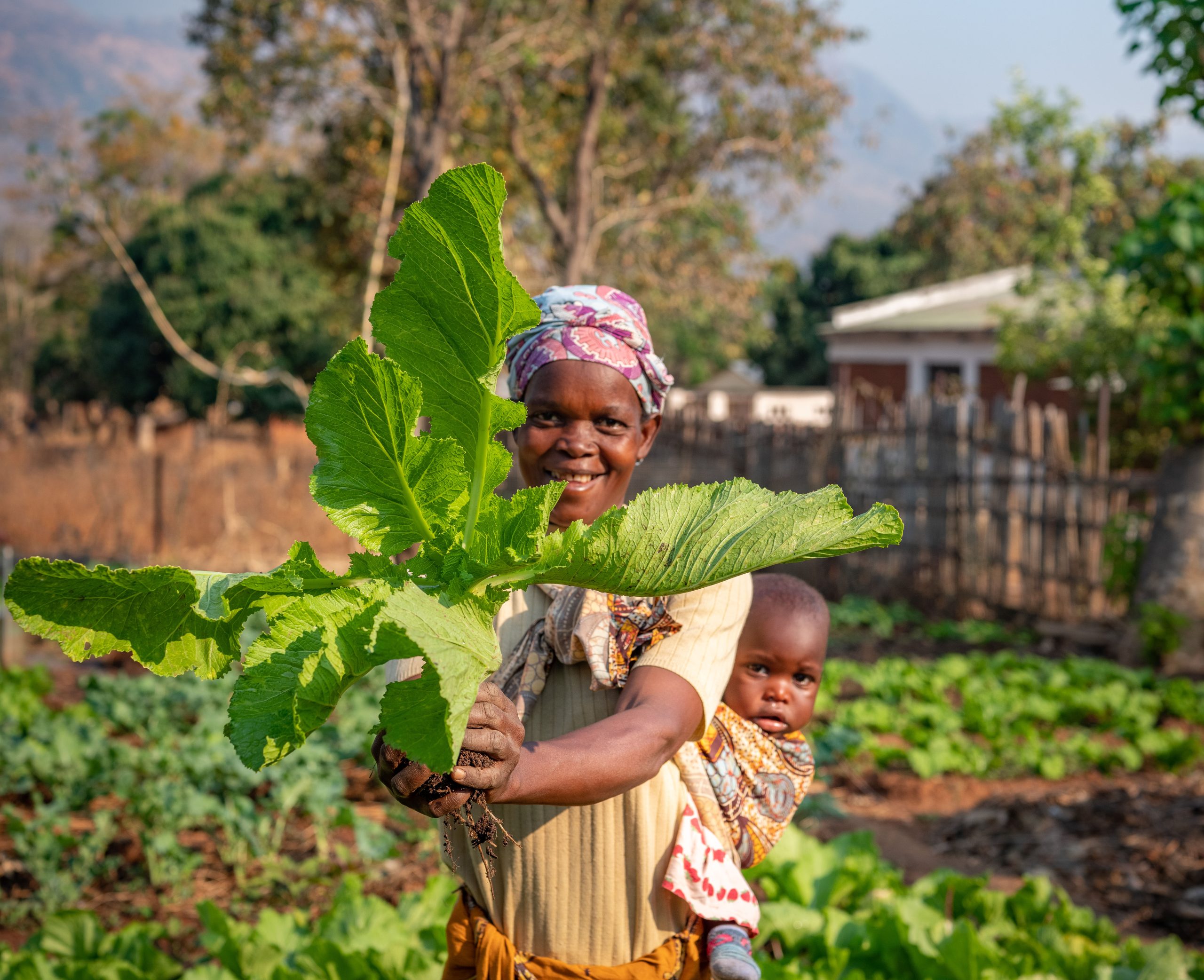 Een vrouw met een kind en groente in een groentetuin