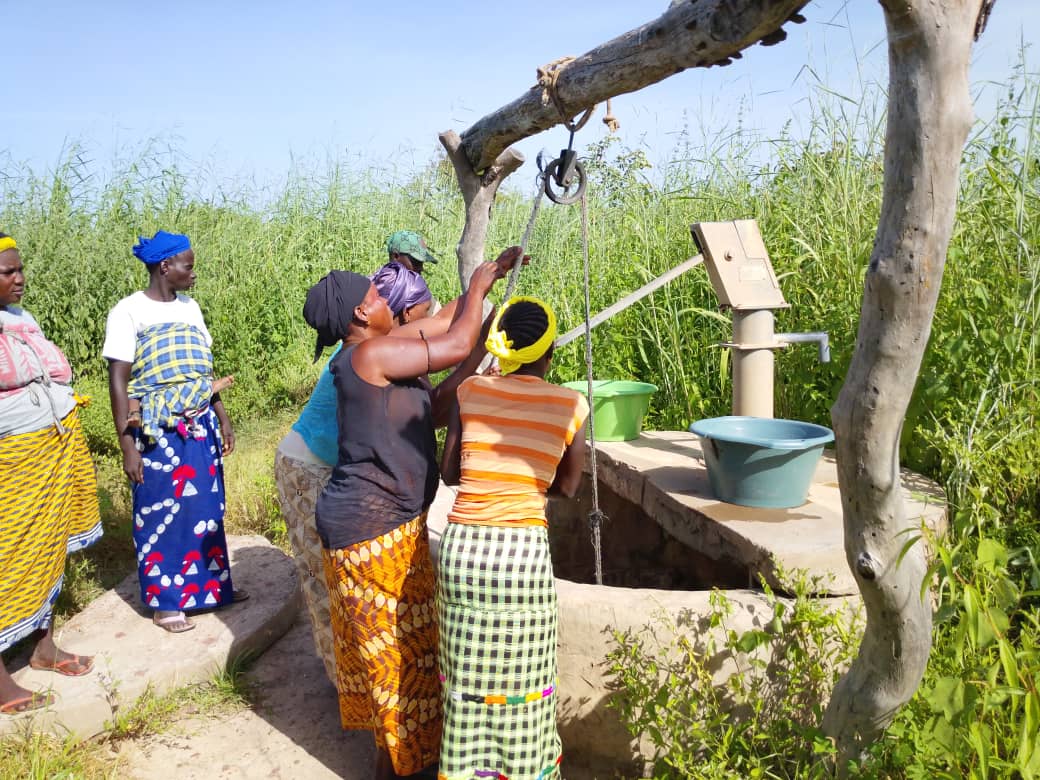 Vrouwen staan bij een waterput om water uit de put te halen.