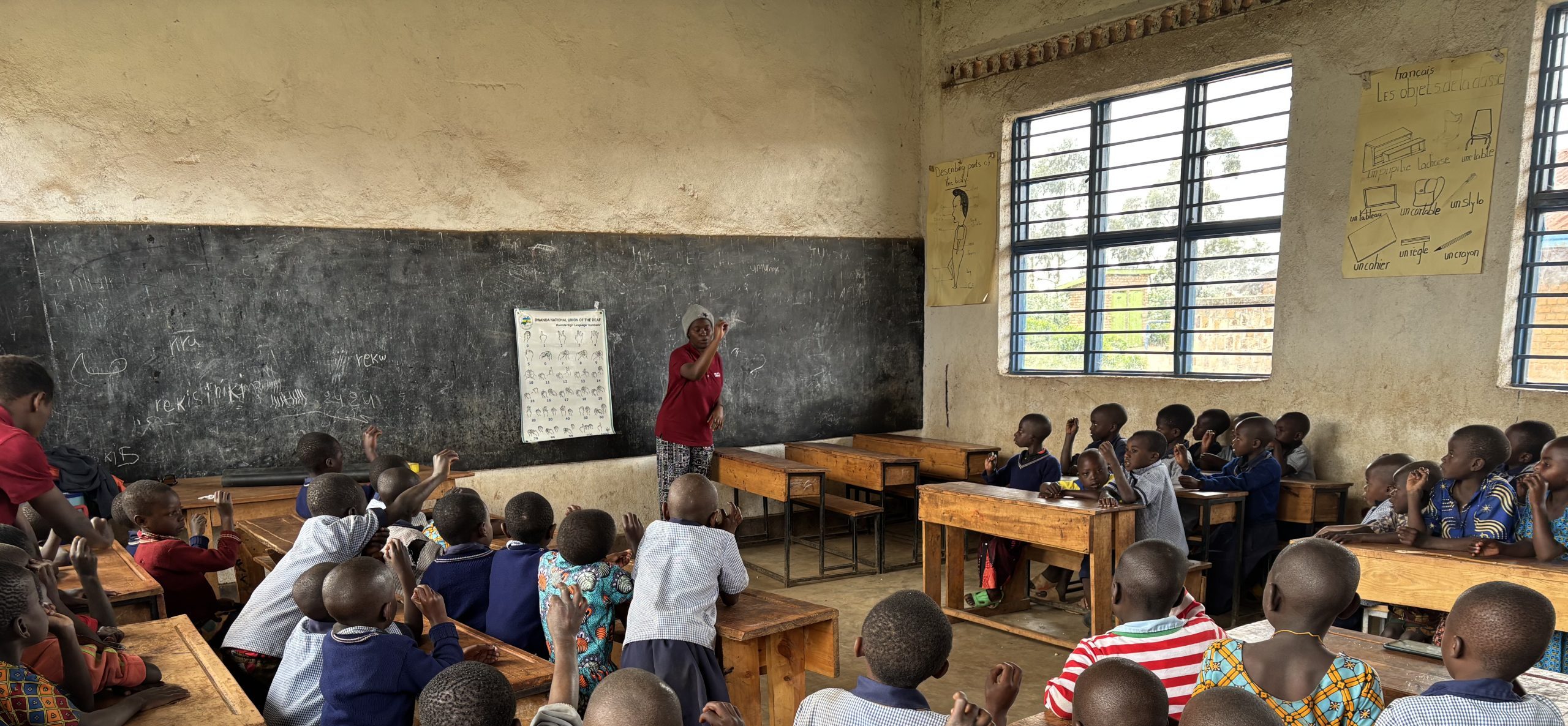 Een groep jongeren kinderen oefent gebarentaal in een klaslokaal.