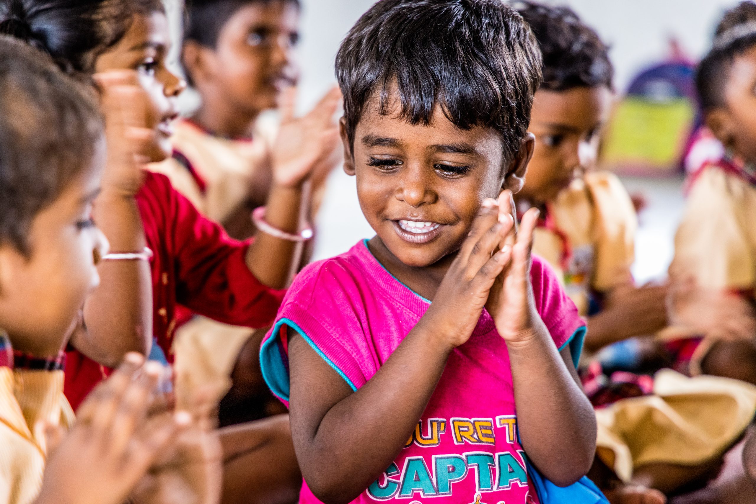 Een lachende jongen in een roze t-shirt