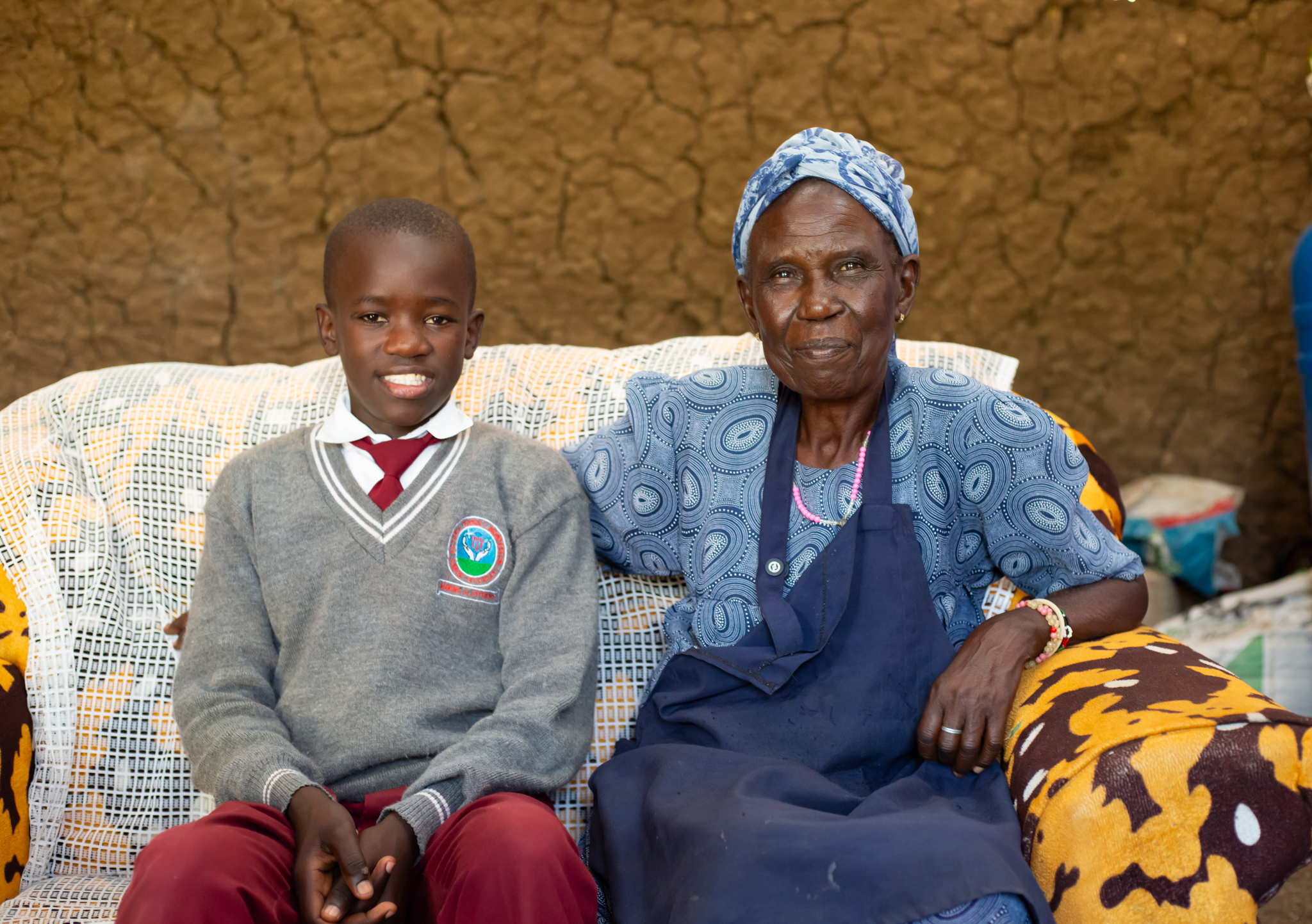 Domnic en zijn oma zitten op een bank en glimlachen naar de camera