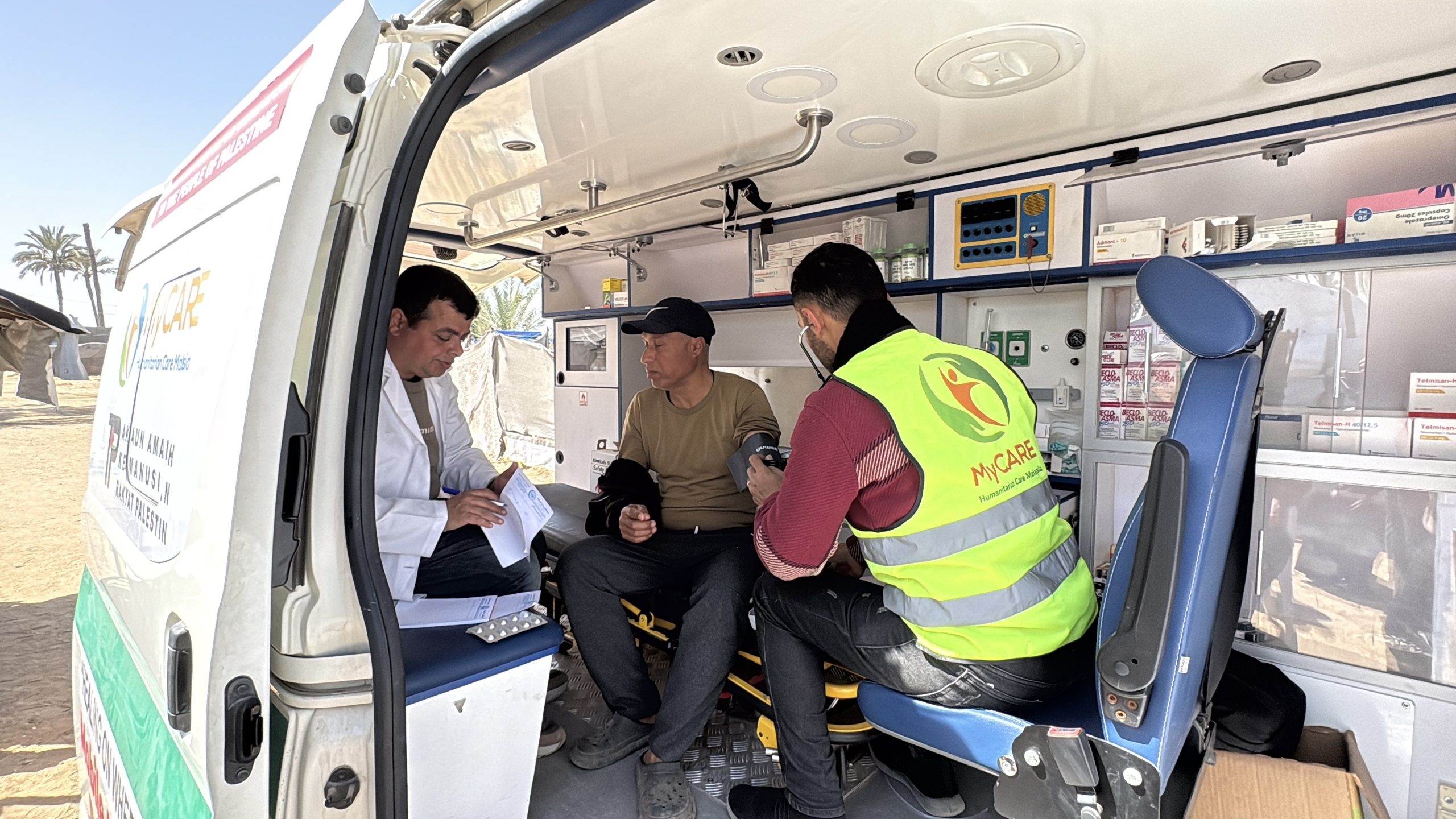 Een man en twee hulpverleners in een mobiele kliniek.