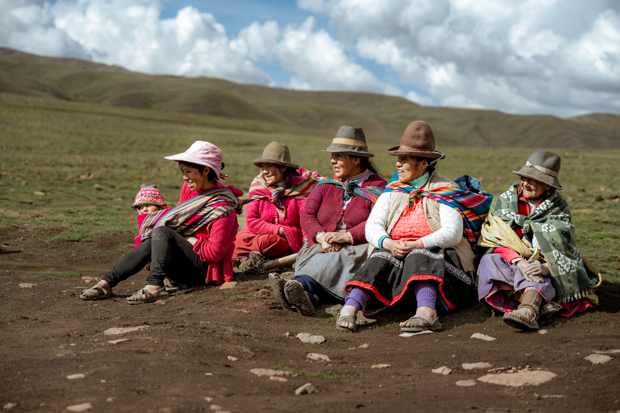 Een groep vrouwen in traditionele kleding zit in een grasland